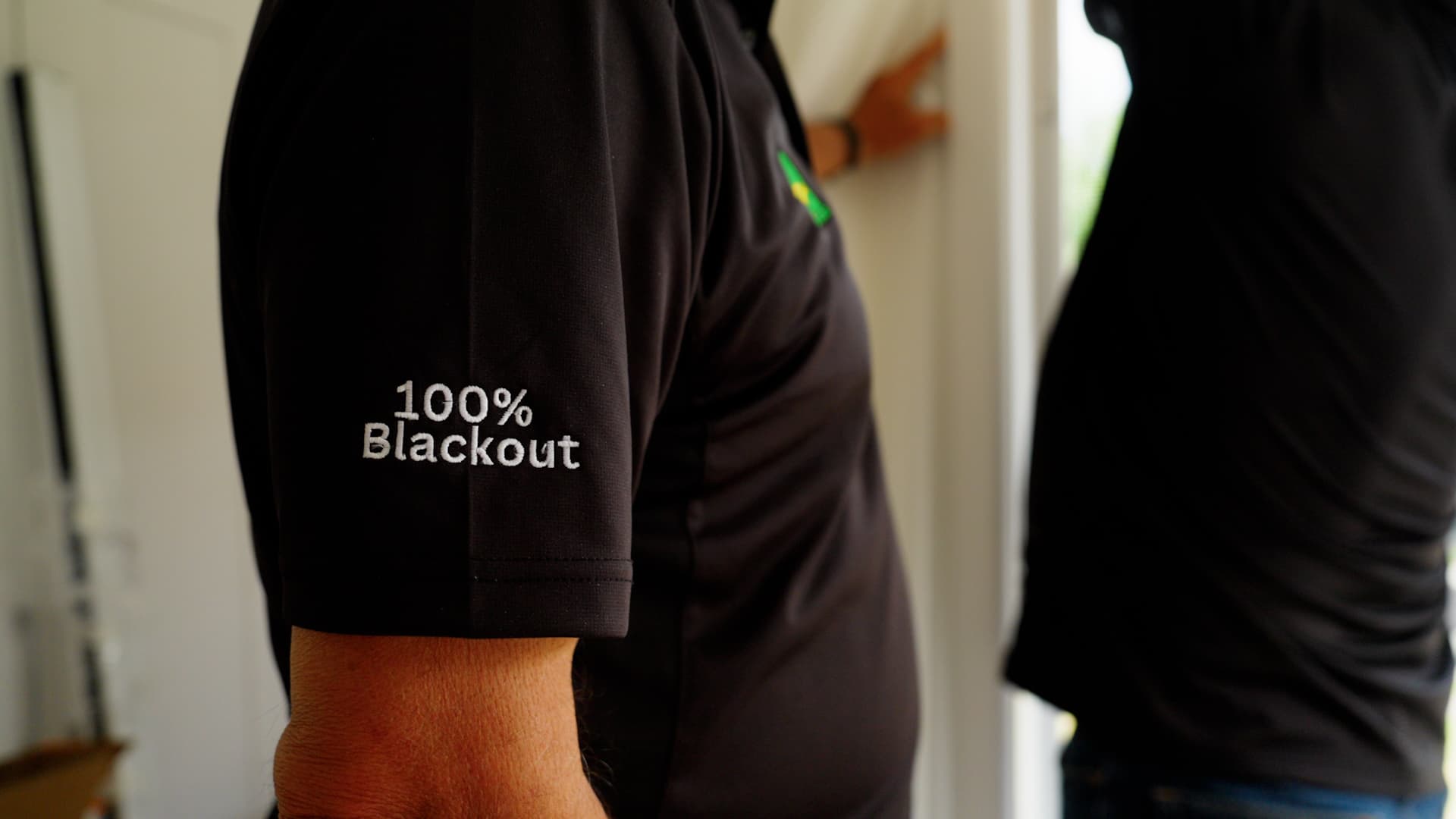 An installer fitting a motorised blackout blind in a bedroom.